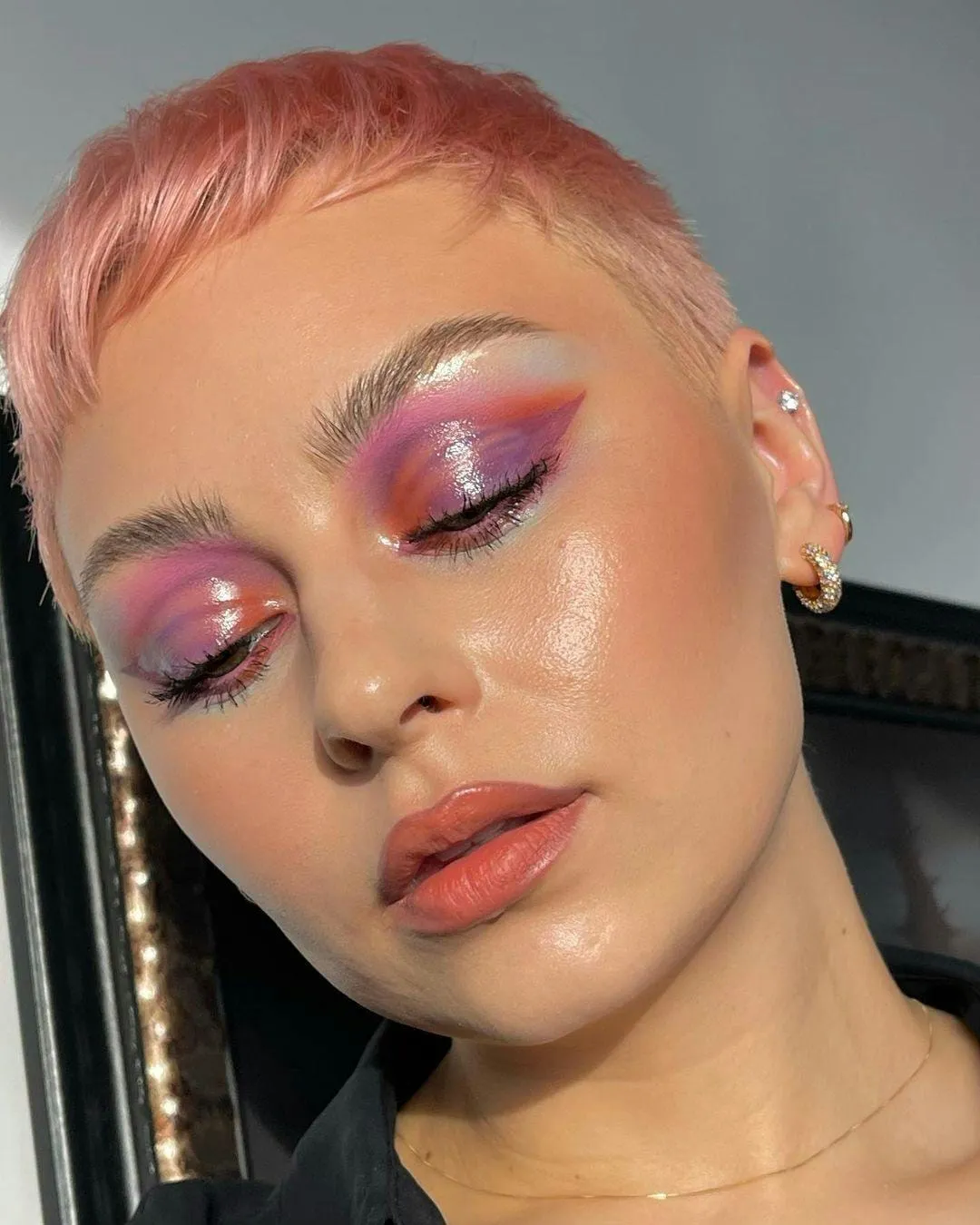 Glossy dewy skin with blended pink and lilac eyeshadow and a soft coral lip
