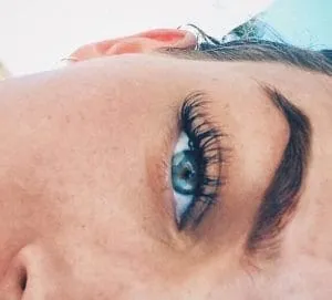 Close-up of an eye with dark, curled eyelash extensions and a natural brow