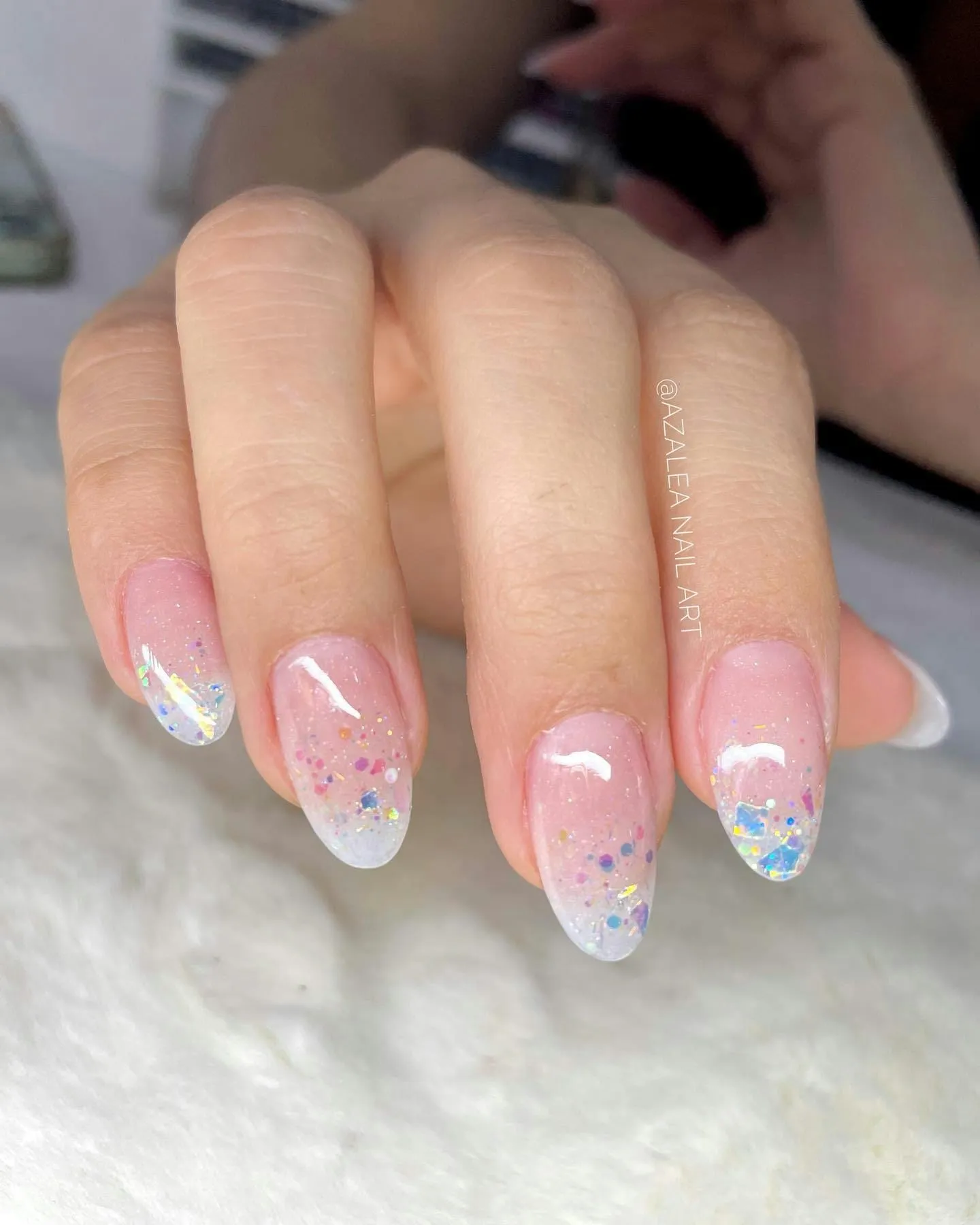 Almond nails in sheer pink with an iridescent glitter gradient towards the tips