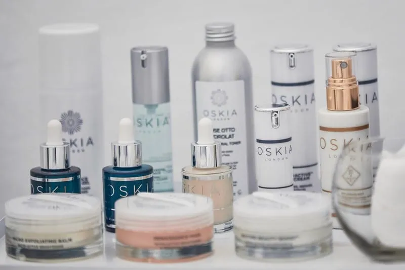 Row of OSKIA London serums, balms and creams set out on a white treatment table