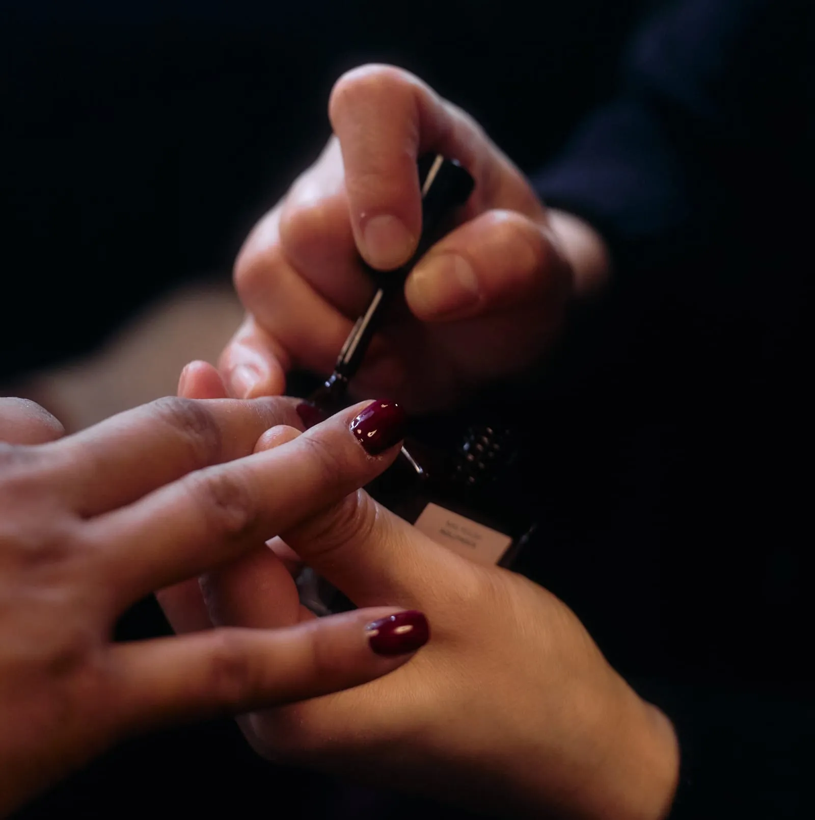 Nail Technician painting a guest's nails deep red at the RIXO Gold collection launch