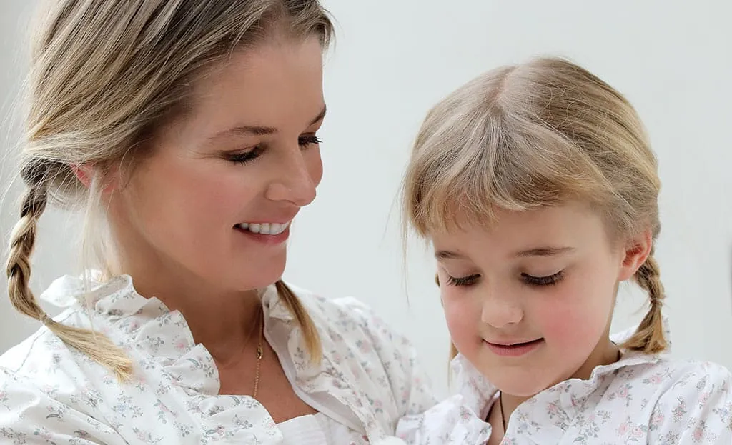 Mother and young daughter in matching floral prints, both wearing side plaits