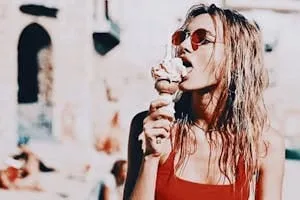 Wet beach hair and red sunglasses while eating an ice cream cone in the sun