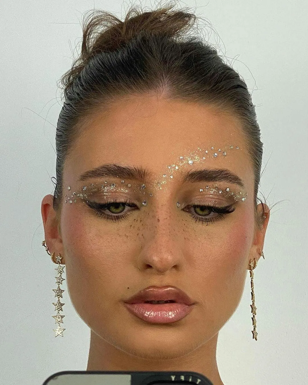 Festive eye look with gold glitter and crystals set along the lids and brows