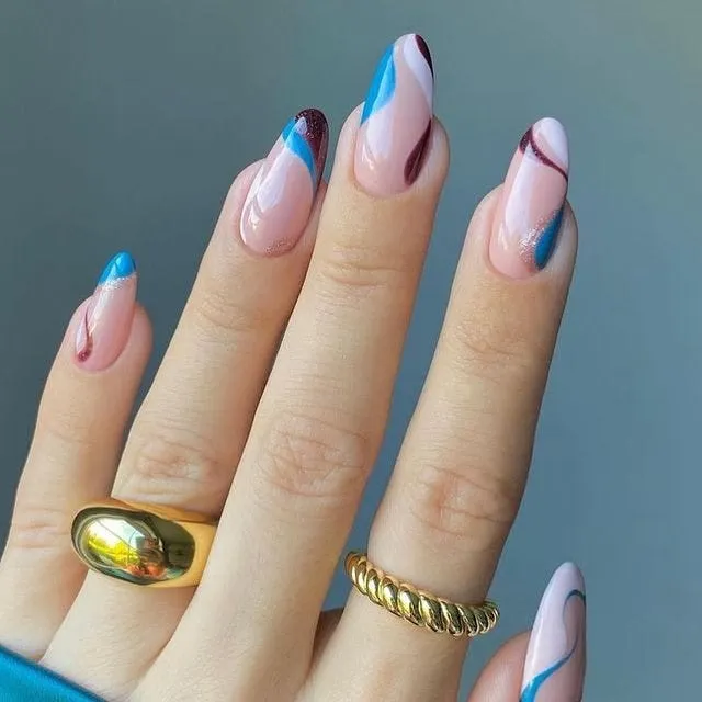 Almond nails with 70s inspired swirls in bright blue and burgundy over a nude base