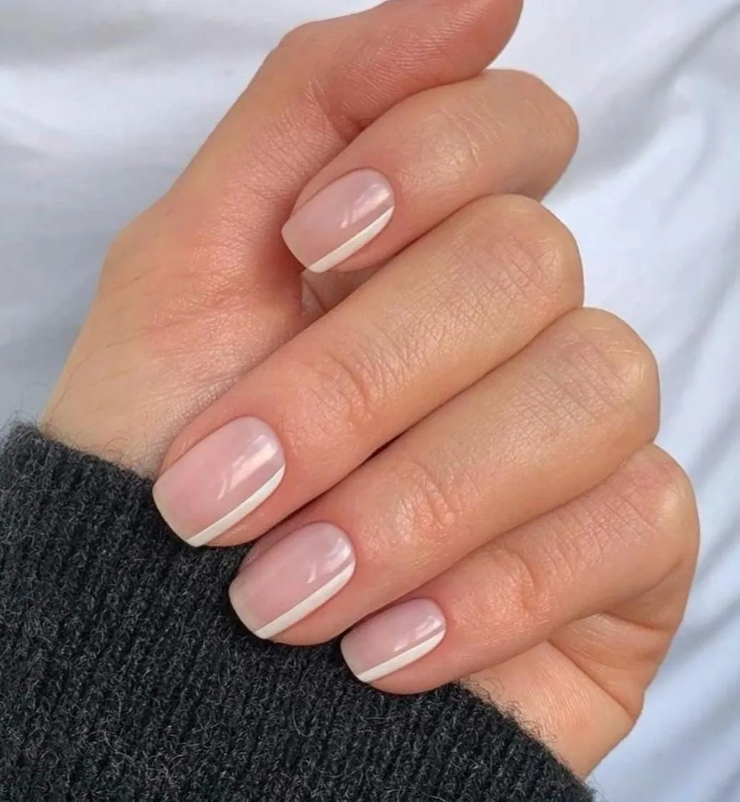 Short squared nude nails with a fine white diagonal line drawn across each tip