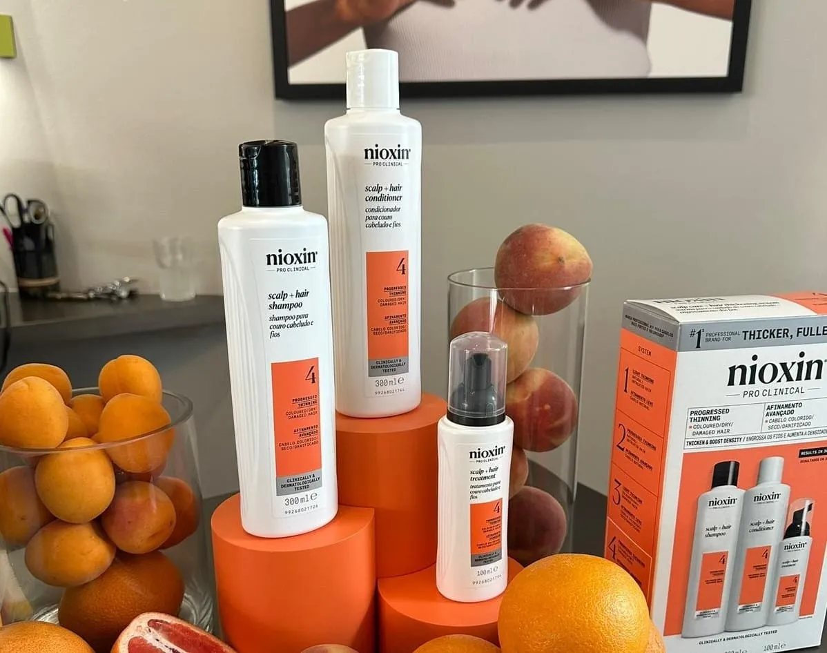 Nioxin scalp and hair products displayed on orange plinths with fresh fruit at a rebrand event
