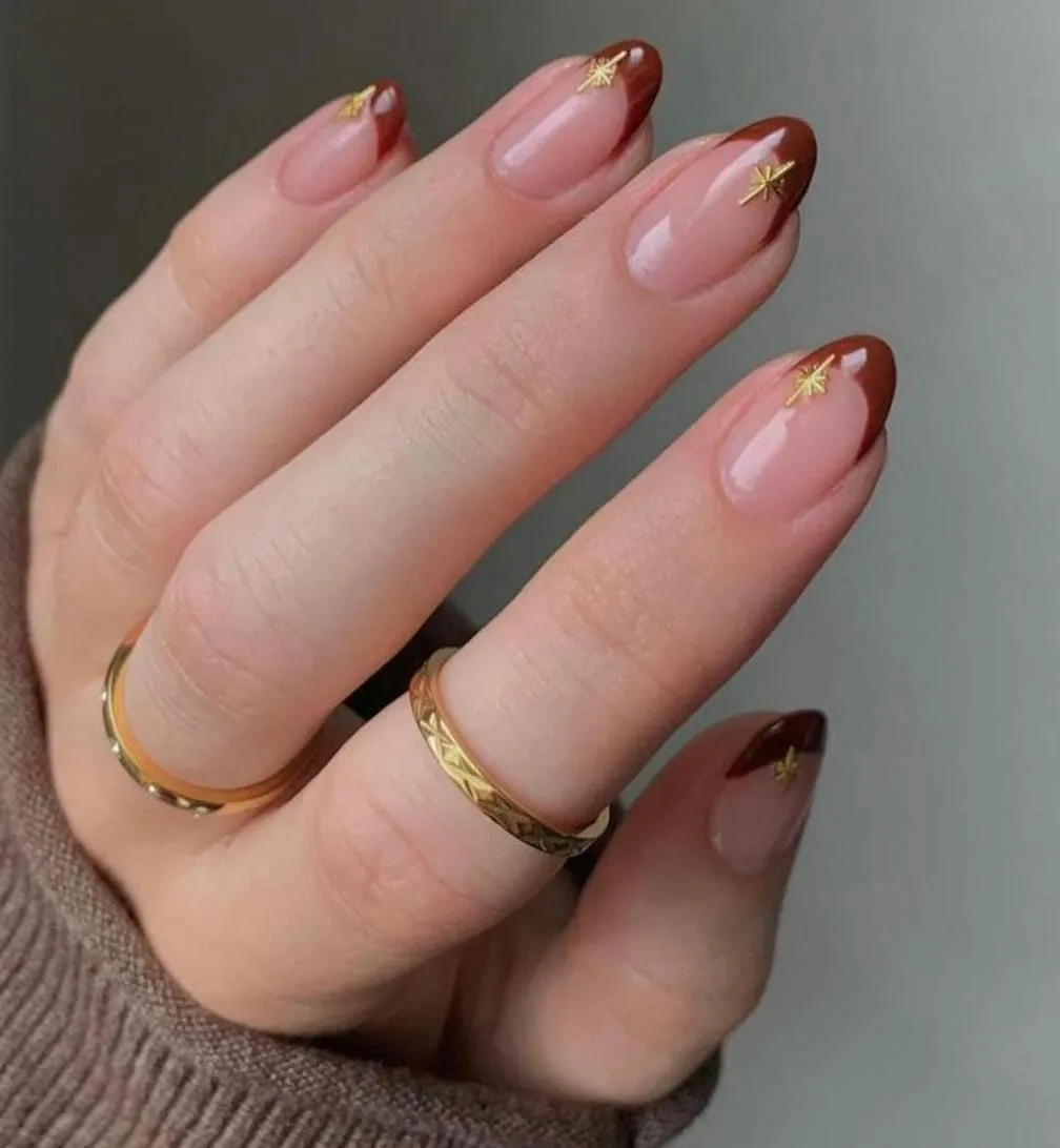 Autumnal nails with rust brown French tips finished with small gold star studs