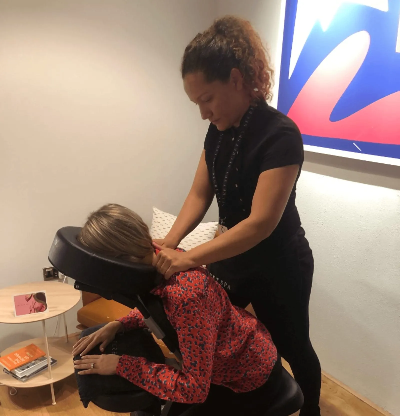 Secret Spa therapist giving a seated chair massage to an office worker during a workplace wellness day