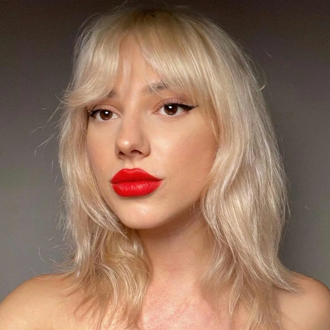 Classic bright red lip worn with soft flicked eyeliner and glowing bare skin