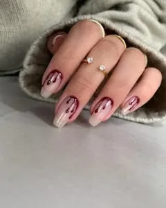 Almond nails with a dripping blood effect in glossy dark red over a nude base