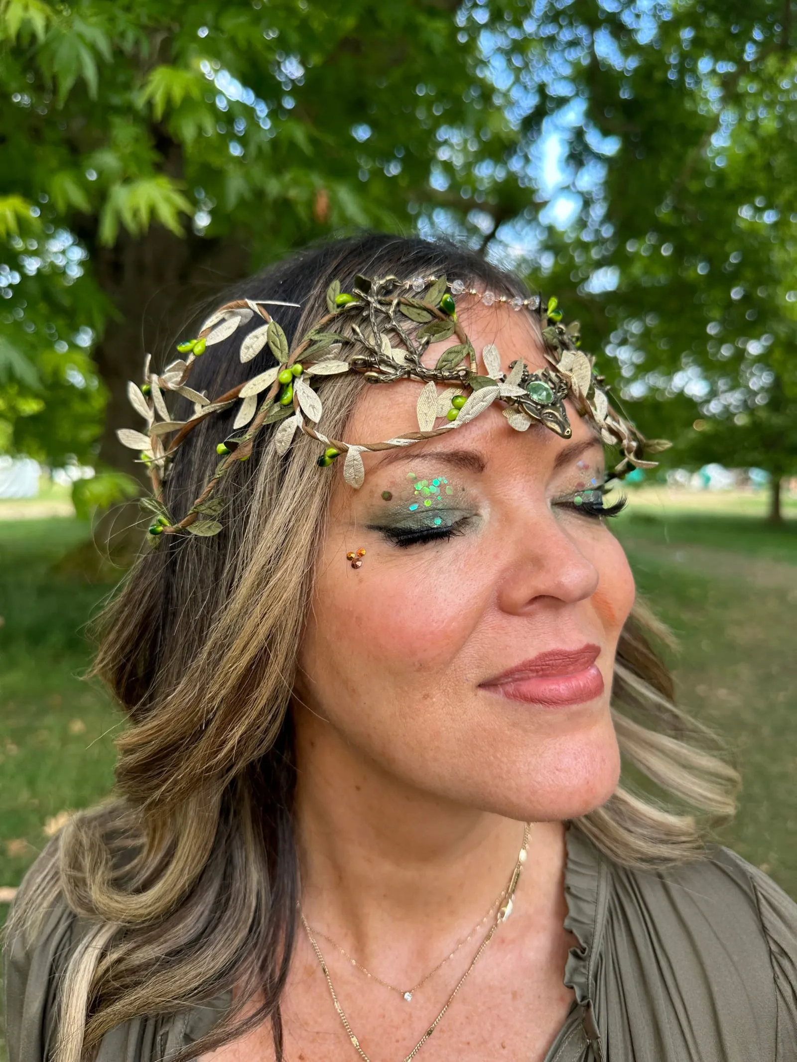 Festival guest wearing a leaf crown with green glitter eye make-up and face gems