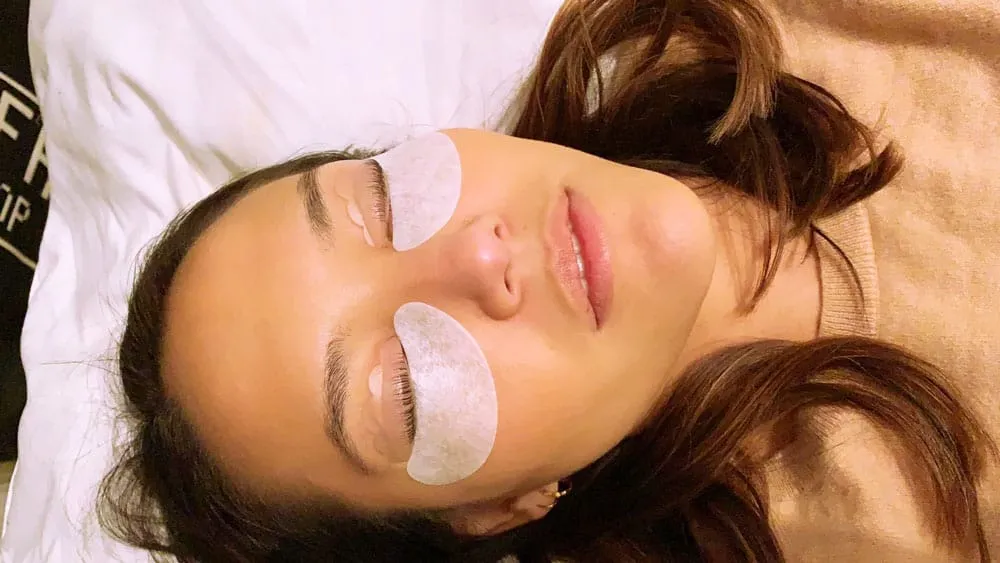 Under-eye pads in place and eyes closed during an LVL lash lift treatment