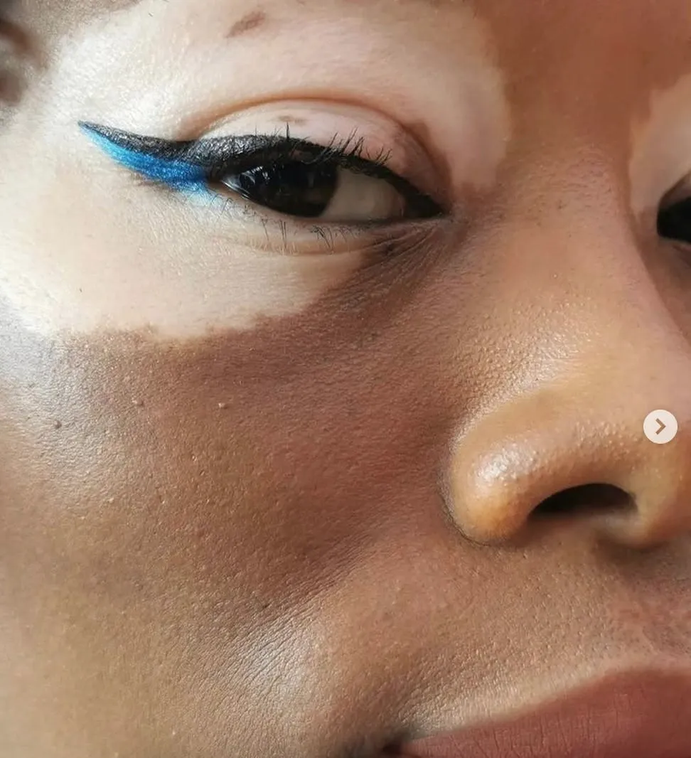 Close-up of a graphic black winged eyeliner finished with a bright blue flick