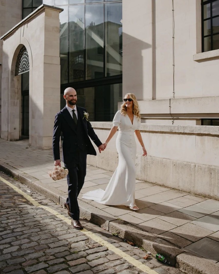 Bride and groom walking a London street, the bride in a fitted dress with a sleek bridal blow-dry