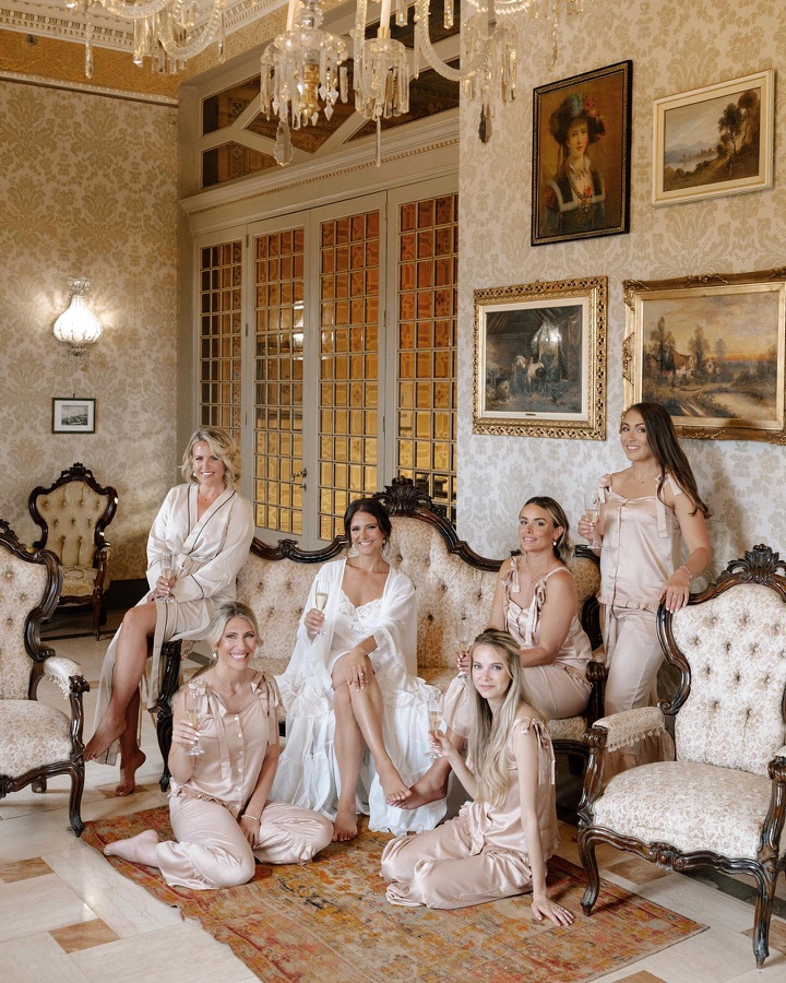Bride and her bridesmaids in silk pyjamas with champagne, hair and make-up finished before the ceremony